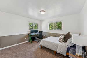 Bedroom featuring a textured ceiling, an office area, and carpet flooring
