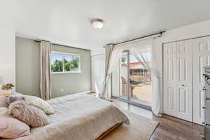 Bedroom with access to exterior, wood finished floors, and two closets