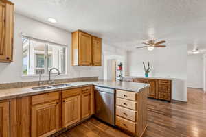 Kitchen with dishwasher, a peninsula, a textured ceiling, ceiling fan, and dark wood-style floors