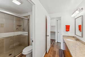 Full bath with vanity, wood finished floors, and a shower stall