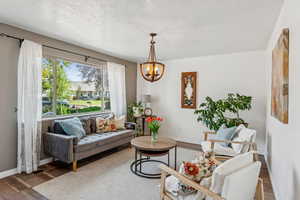 Living room featuring wood finished floors, a chandelier, and a textured ceiling