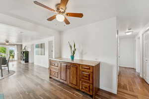 Interior space with a ceiling fan, brown cabinets, wood finished floors, light countertops, and open floor plan