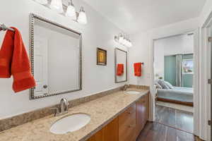 Bathroom featuring double vanity, wood finished floors, and ensuite bath