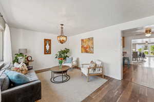 Living area featuring wood finished floors, a ceiling fan, a chandelier, and a textured ceiling