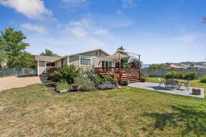 Back of property featuring a wooden deck, a fenced backyard, and a patio area