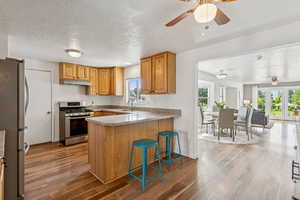 Kitchen with appliances with stainless steel finishes, under cabinet range hood, a ceiling fan, a peninsula, and plenty of natural light