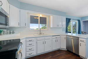 Kitchen with stainless steel appliances, light countertops, and white cabinets