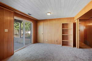 Carpeted spare room with wooden walls