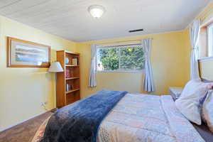 Carpeted bedroom featuring wooden ceiling and baseboards