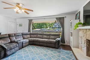 Living room with wood finished floors, ceiling fan, and a fireplace