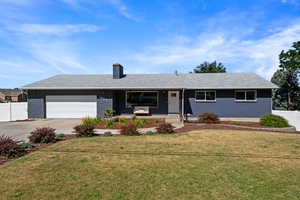 Single story home with brick siding, a garage, a chimney, and driveway