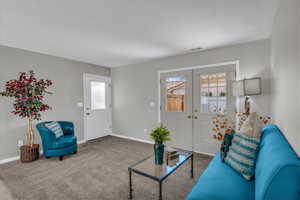 Carpeted living room with french doors and baseboards