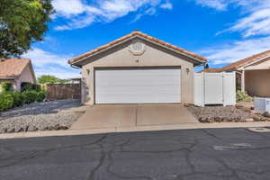 View of front of property featuring a gate, stucco siding, a tile roof, and driveway