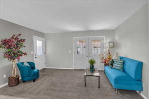 Carpeted living area with french doors and plenty of natural light