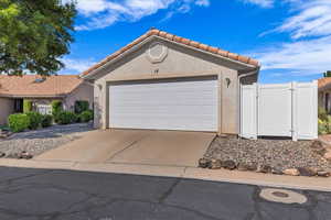 View of front of property featuring stucco siding, a gate, a garage, driveway, and a tiled roof