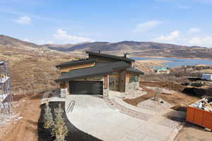 Modern home featuring a mountain view, concrete driveway, stone siding, and a garage