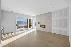 Unfurnished living room with a mountain view, light wood-style flooring, and a tile fireplace