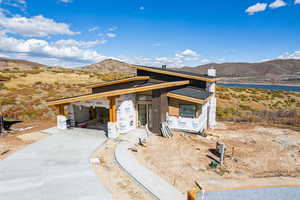 Property under construction featuring board and batten siding, a water and mountain view, a chimney, and covered porch