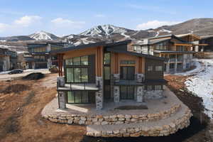 Back of house with a patio area, a mountain view, board and batten siding, stone siding, and a balcony