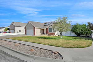 View of front of home featuring brick siding, a garage, roof mounted solar panels, concrete driveway, and roof with shingles
