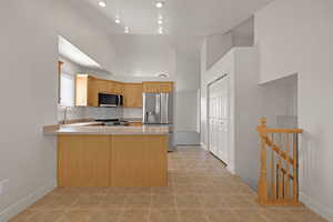 Kitchen featuring stainless steel appliances, light countertops, a peninsula, lofted ceiling, and tasteful backsplash