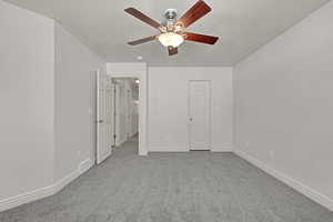 Unfurnished bedroom with a textured ceiling, carpet flooring, and a ceiling fan