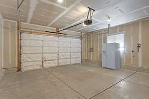 Garage with white fridge with ice dispenser and a garage door opener