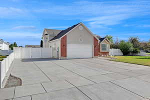 View of home's exterior featuring driveway, a garage, roof mounted solar panels, a gate, and brick siding