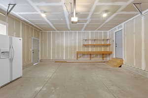 Garage featuring white fridge with ice dispenser and a garage door opener