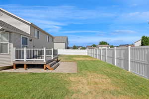 Fenced backyard featuring a wooden deck and a patio area