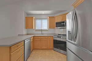 Kitchen with stainless steel appliances, light tile patterned floors, decorative backsplash, light countertops, and a peninsula