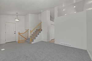 Carpeted entrance foyer with stairs, a textured ceiling, recessed lighting, and vaulted ceiling