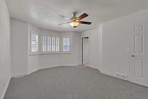 Carpeted spare room with ceiling fan and a textured ceiling