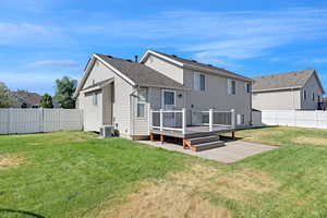 Back of property with a fenced backyard, a deck, and roof with shingles