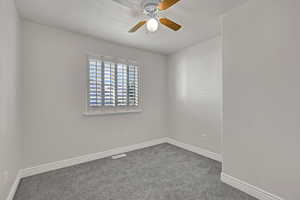 Empty room with ceiling fan, carpet floors, and a textured ceiling