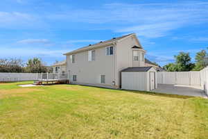 Back of property featuring a storage shed, a fenced backyard, a deck, and a patio area