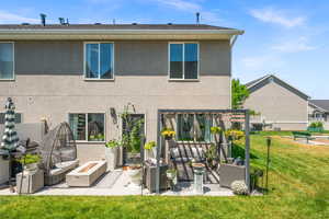 Rear view of house featuring a patio, an outdoor living space with a fire pit, stucco siding, and a lawn