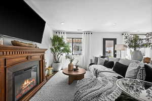 Living room featuring a glass covered fireplace and recessed lighting