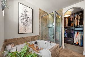 Bathroom featuring a bath, a stall shower, a spacious closet, and tile patterned flooring