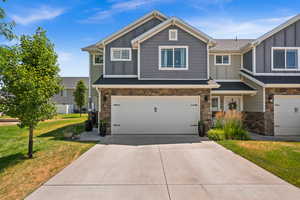 View of front facade featuring board and batten siding, stone siding, an attached garage, and concrete driveway
