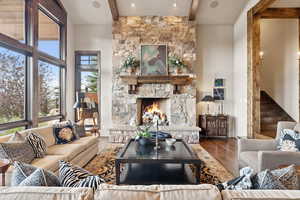 Living area featuring beamed ceiling, healthy amount of natural light, a fireplace, stairs, and wood finished floors