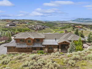 View of front of home with a standing seam roof, a metal roof, stone siding, and a chimney