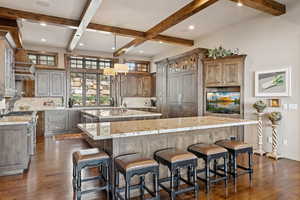 Kitchen with a center island with sink, beam ceiling, backsplash, dark wood-style flooring, and recessed lighting