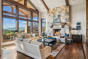 Living room featuring beam ceiling, high vaulted ceiling, a fireplace, dark wood-style flooring, and a mountain view
