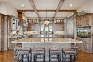 Kitchen featuring a center island, beam ceiling, backsplash, dark wood-style floors, and a kitchen bar