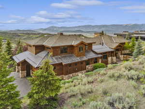 View of front of home featuring a standing seam roof, stone siding, a metal roof, and a mountain view