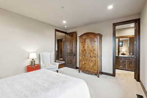 Bedroom with connected bathroom, light carpet, and recessed lighting