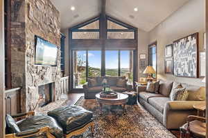 Living area with a fireplace, wood finished floors, high vaulted ceiling, beamed ceiling, and recessed lighting