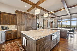 Kitchen with a warming drawer, coffered ceiling, a large island with sink, dark wood-type flooring, and beam ceiling