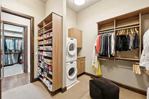 Laundry room featuring cabinet space, estacked washer and dryer, and light colored carpet